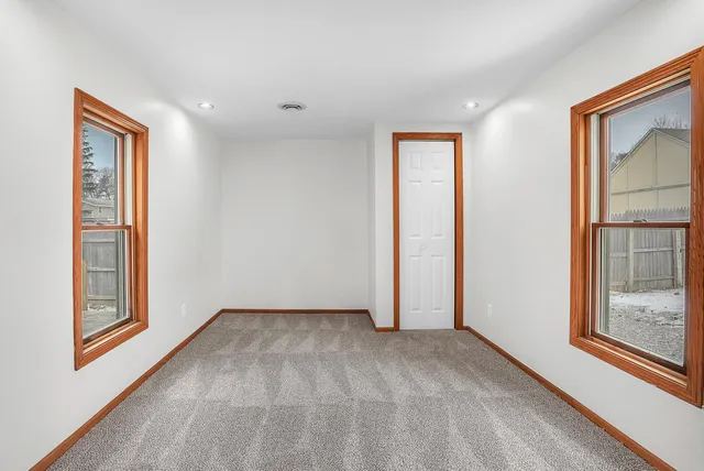 a view of an empty room with window and wooden floor