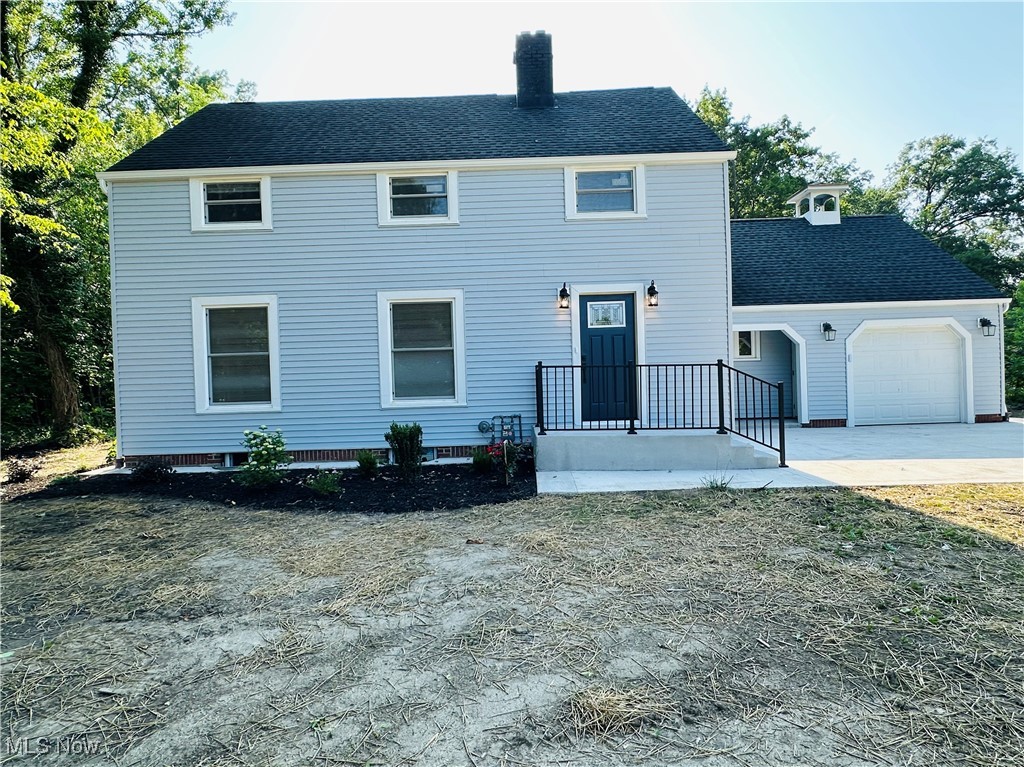 568 North Road Southeast Warren, OH 44484 - Photo 10 of 49 Colonial inspired home featuring an attached garage, concrete driveway, a shingled roof, and a chimney