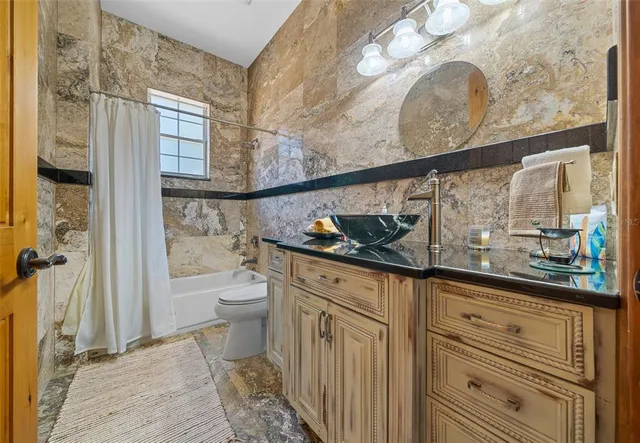 a bathroom with a granite countertop sink a toilet and a shower curtain