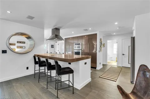 a living room with stainless steel appliances furniture a rug and white walls