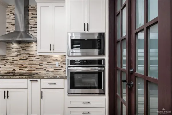 a kitchen with granite countertop white cabinets and stainless steel appliances