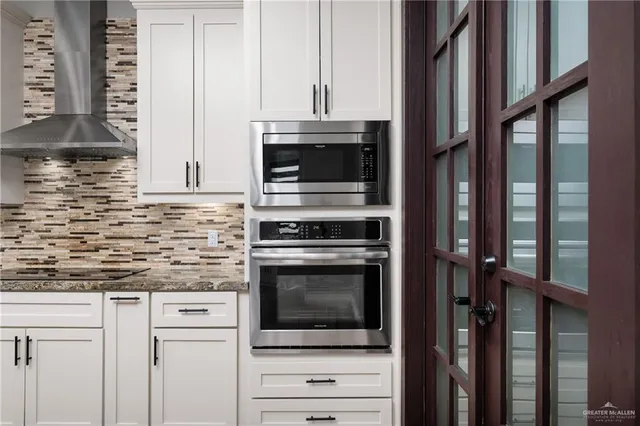 a kitchen with granite countertop white cabinets and stainless steel appliances