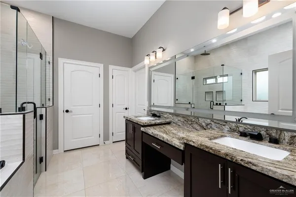 a bathroom with a granite countertop sink two mirror and a shower