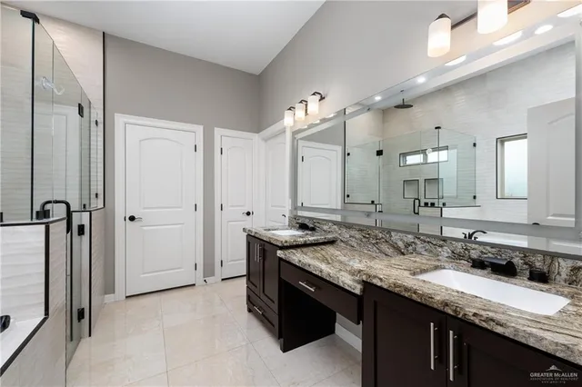 a bathroom with a granite countertop sink two mirror and a shower