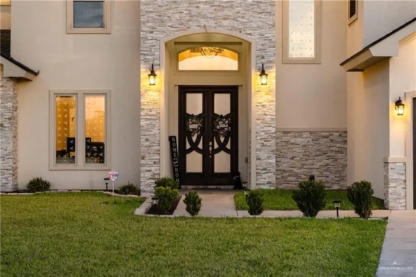 a view of a house with a small yard plants and large tree