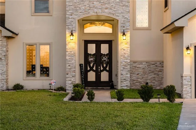 a view of a house with a small yard plants and large tree