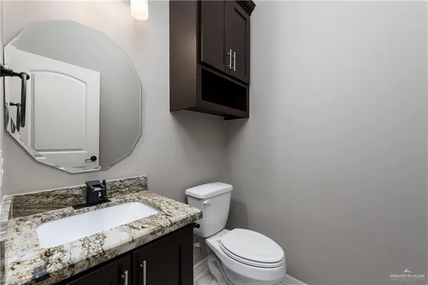 a bathroom with a granite countertop toilet sink and mirror