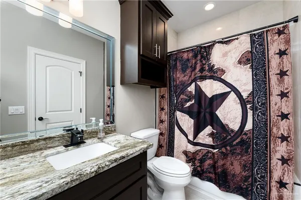 a bathroom with a granite countertop toilet sink and mirror