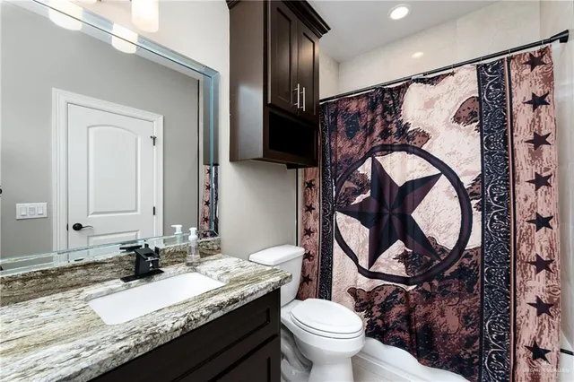 a bathroom with a granite countertop toilet sink and mirror