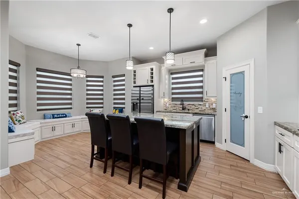 a kitchen with stainless steel appliances granite countertop a kitchen island a stove a table and chairs