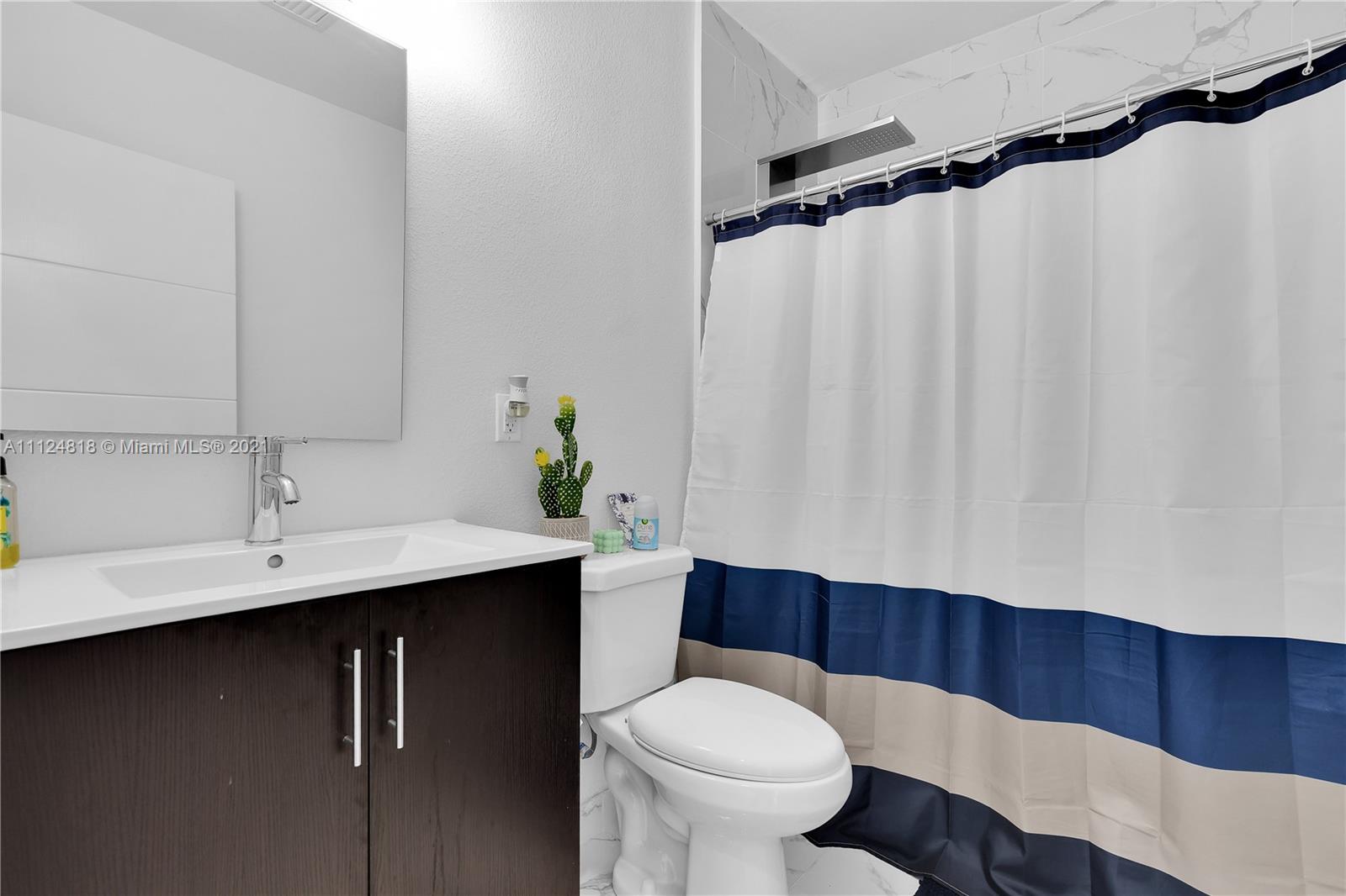 25807 Southwest 139th Court Homestead, FL 33032 - Photo 24 of 32 a bathroom with a sink a toilet and shower curtain