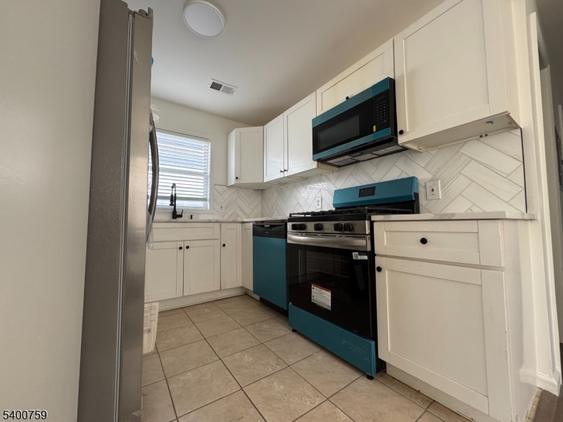 121 12th Avenue Paterson, NJ 07501 - Photo 7 of 14 a kitchen with stainless steel appliances granite countertop a stove a sink and a microwave