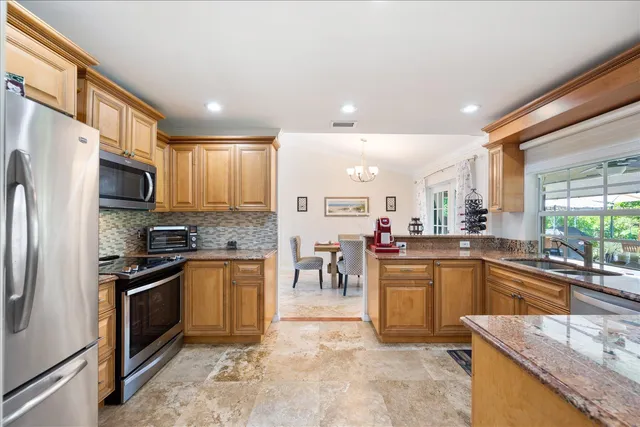 a kitchen with stainless steel appliances granite countertop a refrigerator and a stove top oven