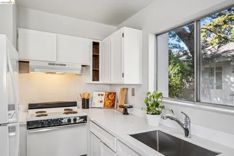 a kitchen with stainless steel appliances a sink a stove and white cabinets next to a window
