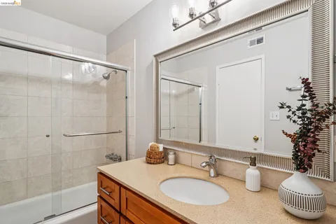 a bathroom with a granite countertop sink a mirror and a shower