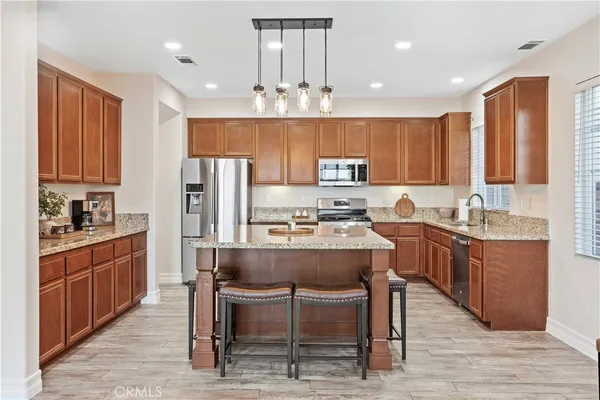 a kitchen with kitchen island granite countertop wooden cabinets and refrigerator