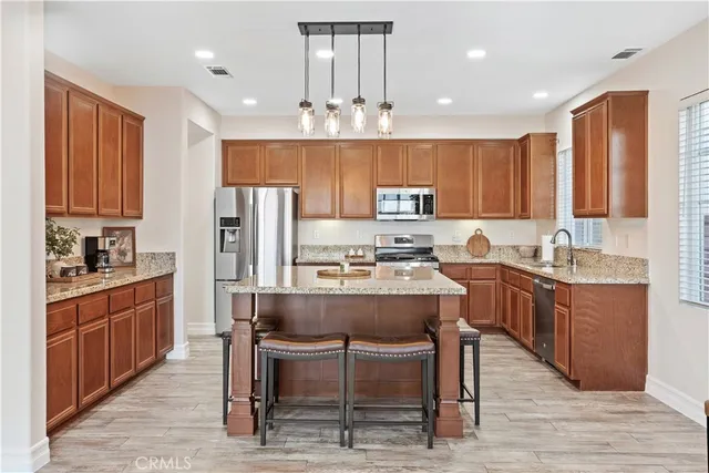a kitchen with kitchen island granite countertop wooden cabinets and refrigerator