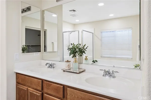 a bathroom with double vanity sinks a large mirror and a shower