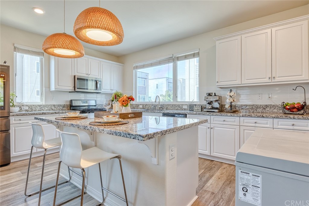8000 Olive Lane Downey, CA 90241 - Photo 6 of 39 a kitchen with kitchen island granite countertop a stove a sink and white cabinets