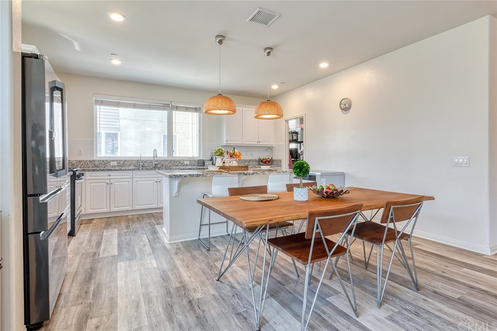 8000 Olive Lane Downey, CA 90241 - Photo 7 of 39 a room with stainless steel appliances kitchen island granite countertop a table chairs and a wooden floor