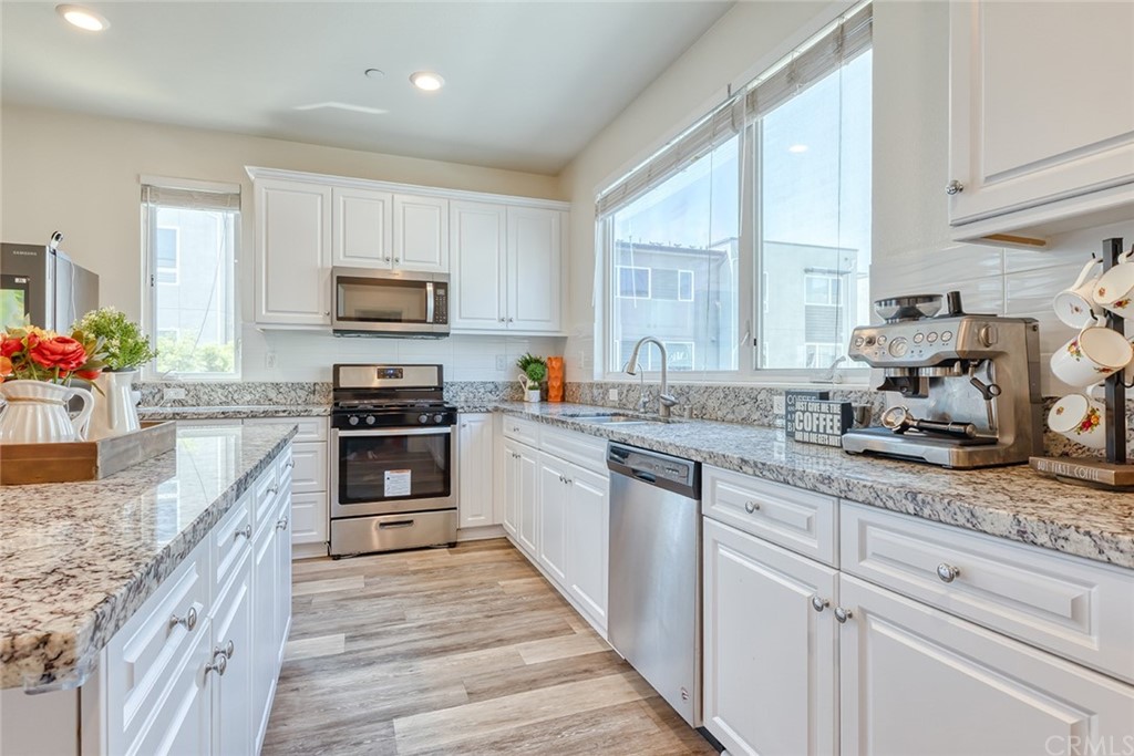 8000 Olive Lane Downey, CA 90241 - Photo 8 of 39 a kitchen with kitchen island granite countertop a sink cabinets and stainless steel appliances