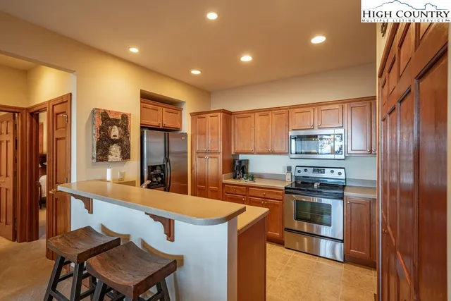 a kitchen with stainless steel appliances kitchen island granite countertop a refrigerator a stove top oven and a sink with wooden floor