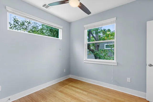 an empty room with wooden floor and windows