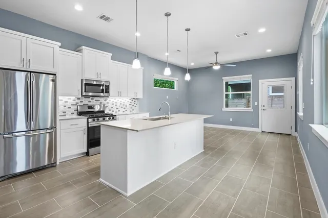 a large kitchen with kitchen island a large counter top stainless steel appliances and cabinets