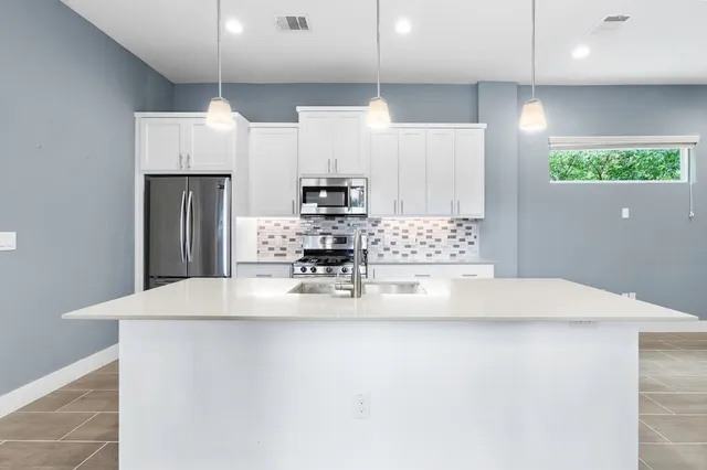 a kitchen with kitchen island a counter top space a sink cabinets and stainless steel appliances