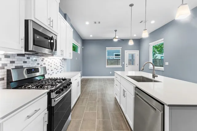 a kitchen with stainless steel appliances a sink a stove top oven a refrigerator cabinets and a window