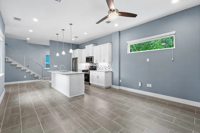 a view of a kitchen with kitchen island stainless steel appliances a sink a counter top space cabinets and a window