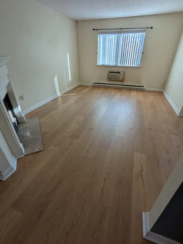 an empty room with fireplace and wooden floor