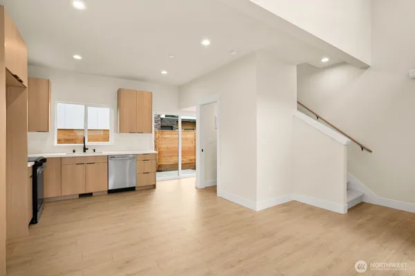 a large white kitchen with a stove a sink dishwasher and a refrigerator with wooden floor