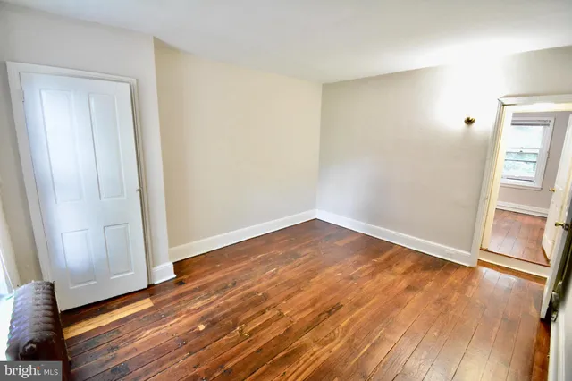 an empty room with wooden floor and entrance