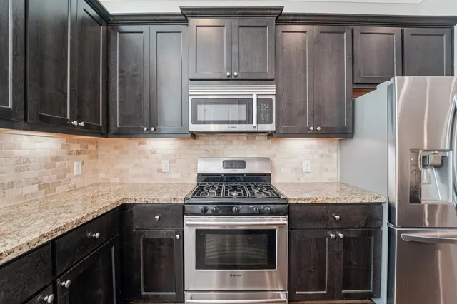 a kitchen with stainless steel appliances granite countertop a stove a sink and a microwave