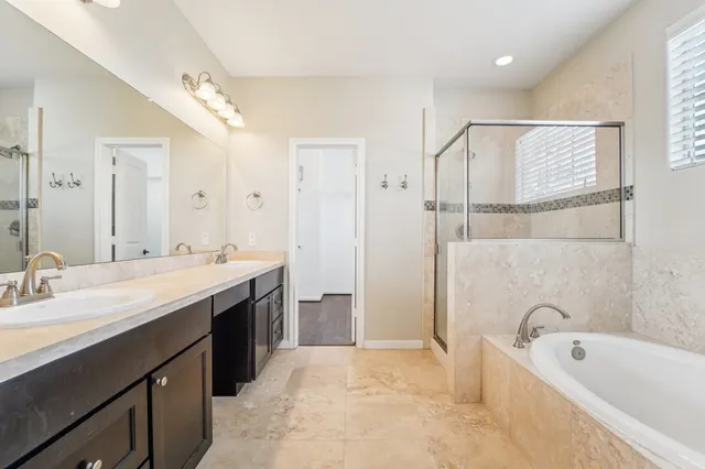 a spacious bathroom with a tub sink shower and mirror