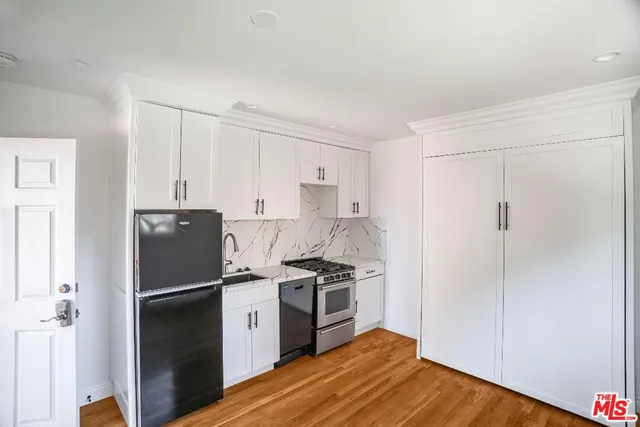 a kitchen with a refrigerator a stove and white cabinets