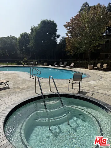 a view of swimming pool with a bench and trees in the background