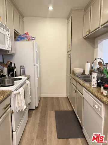 a kitchen with granite countertop white cabinets and white appliances