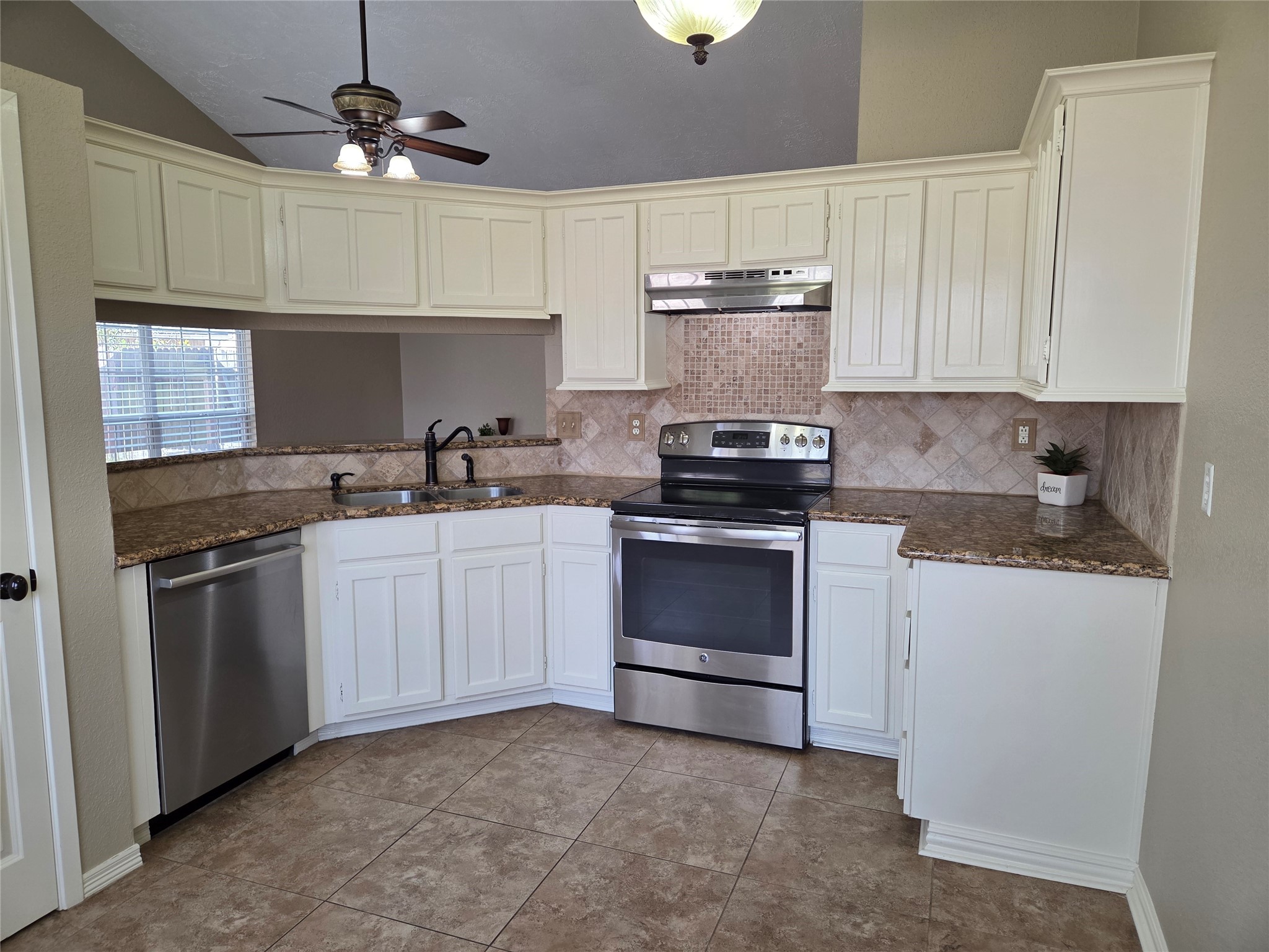 4203 Spinks Creek Lane Spring, TX 77388 - Photo 3 of 14 This kitchen features white cabinetry, granite countertops, and stainless steel appliances, including a Bosch dishwasher and electric range. It has a mosaic backsplash, a double sink, and chandelier, creating a bright and functional space. Nice sized pantry.