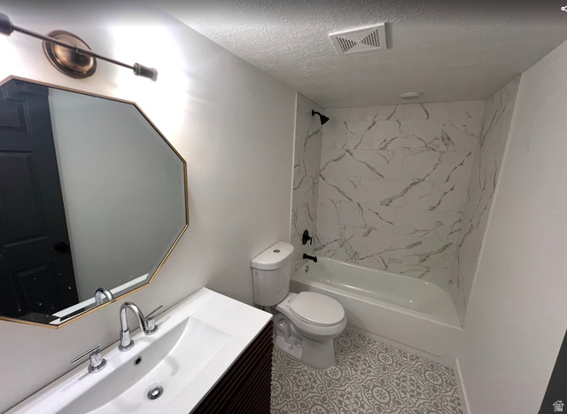 545 23rd Street Ogden, UT 84401 - Photo 21 of 28 Bathroom featuring a white bathtub with a marble-look surround, a white toilet, and patterned floor tiles