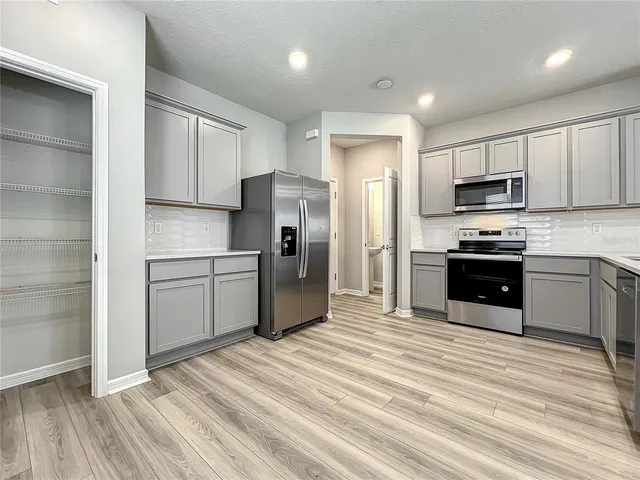 a kitchen with stainless steel appliances granite countertop a sink and a refrigerator