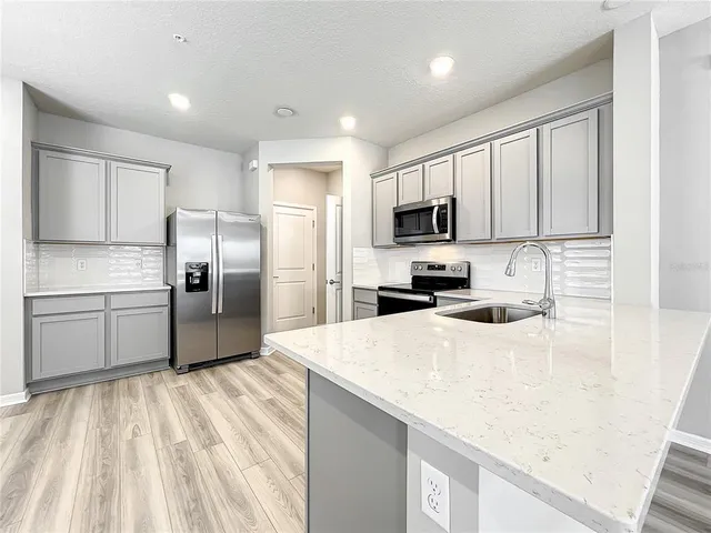 a view of a living room with wooden floor and a kitchen