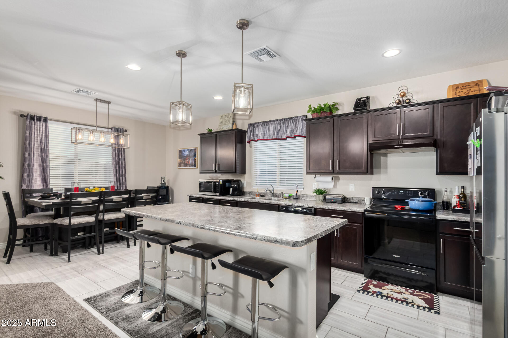10637 West Crown King Road Tolleson, AZ 85353 - Photo 6 of 19 a kitchen with stainless steel appliances granite countertop a sink a stove and chairs