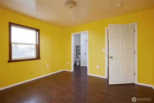 a view of an empty room with wooden floor and closet