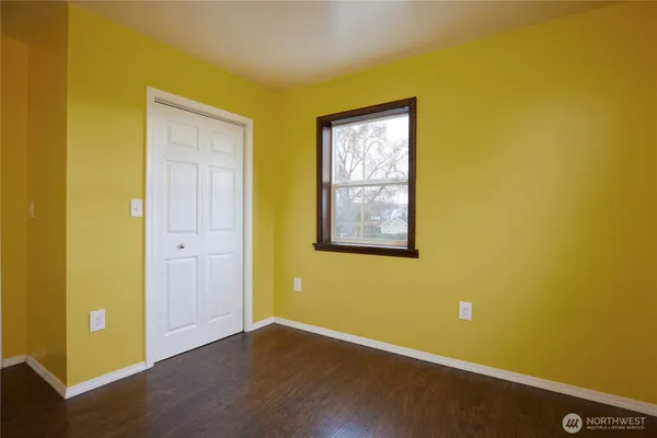 a view of an empty room with wooden floor and windows