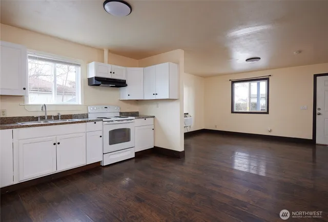 a kitchen with granite countertop wooden floors stainless steel appliances and window