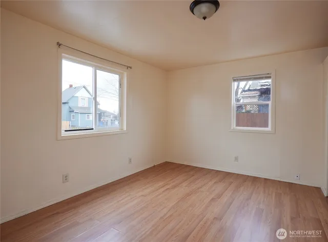 an empty room with wooden floor and windows