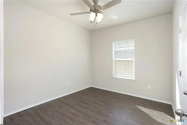 an empty room with a window and a fan