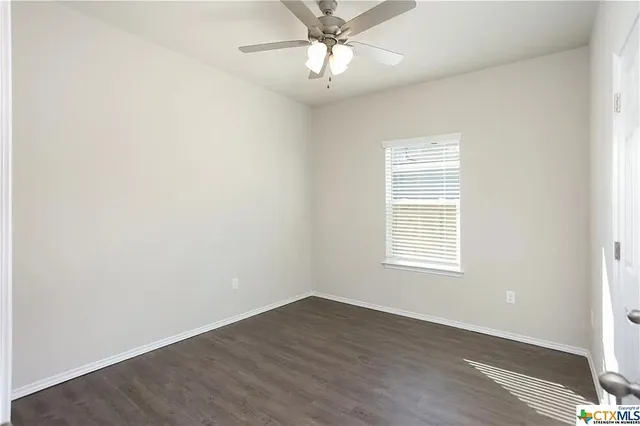 an empty room with a window and a fan
